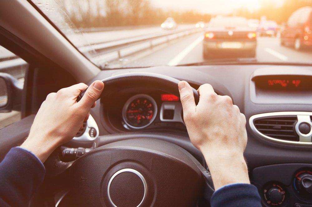motorista com as duas mãos no volante.