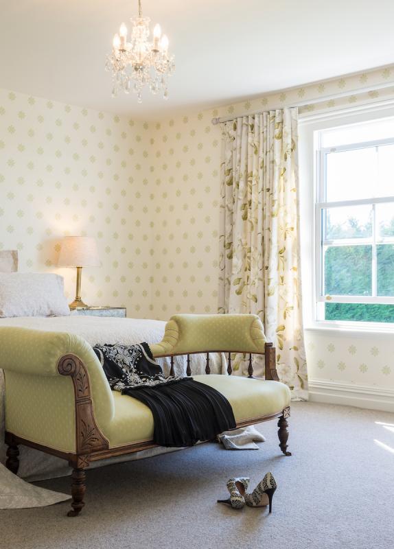 Sitting room with patterned wallpaper, classic sofa, draped curtains and natural light