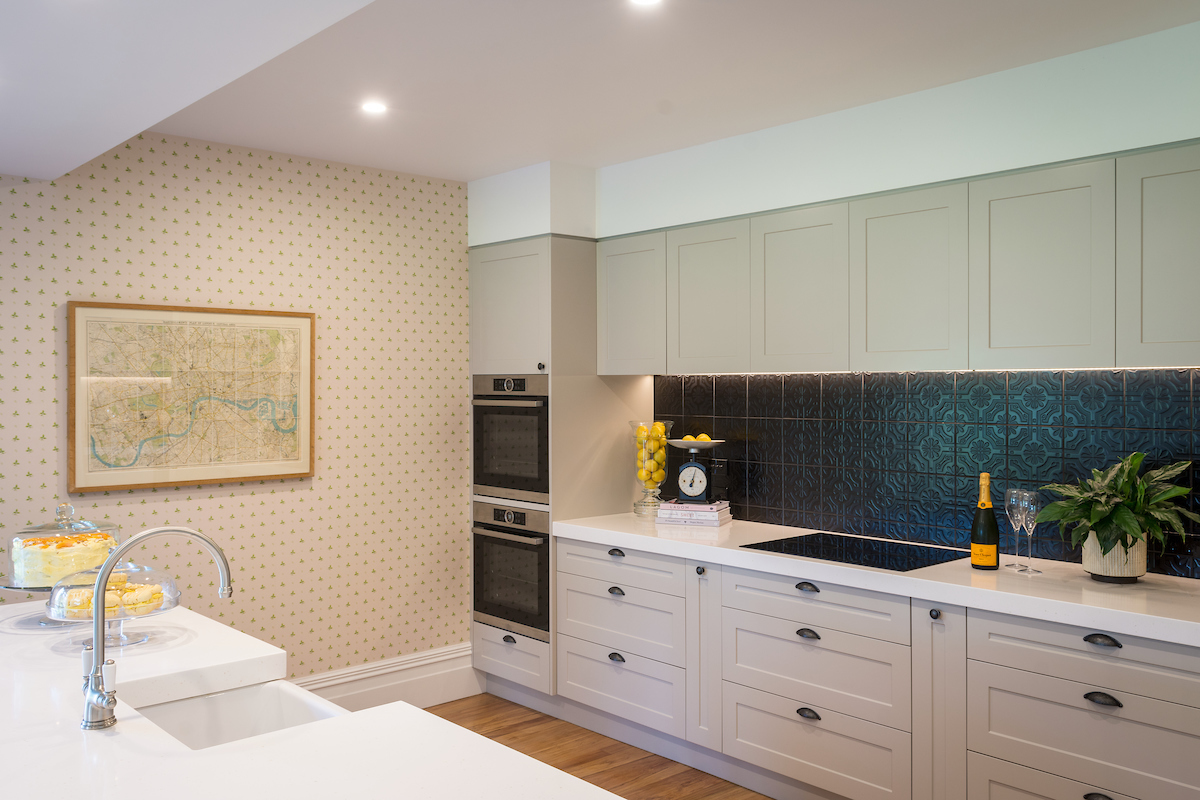 Modernised kitchen with white cabinetry, integrated appliances and large window overlooking the rural landscape