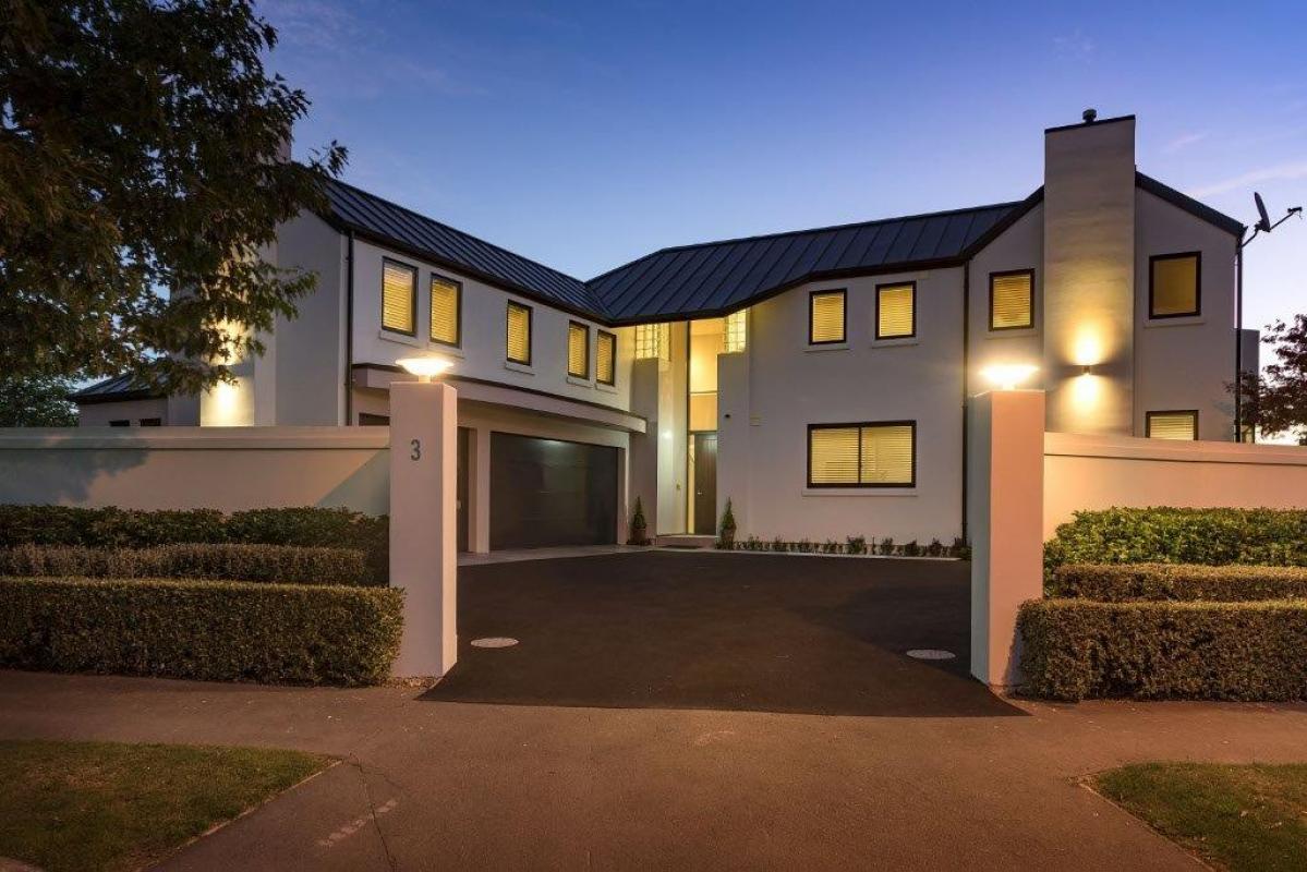 Exterior evening view of the St Albans townhouse showing white plaster cladding, contemporary roofline and warm interior lighting at dusk