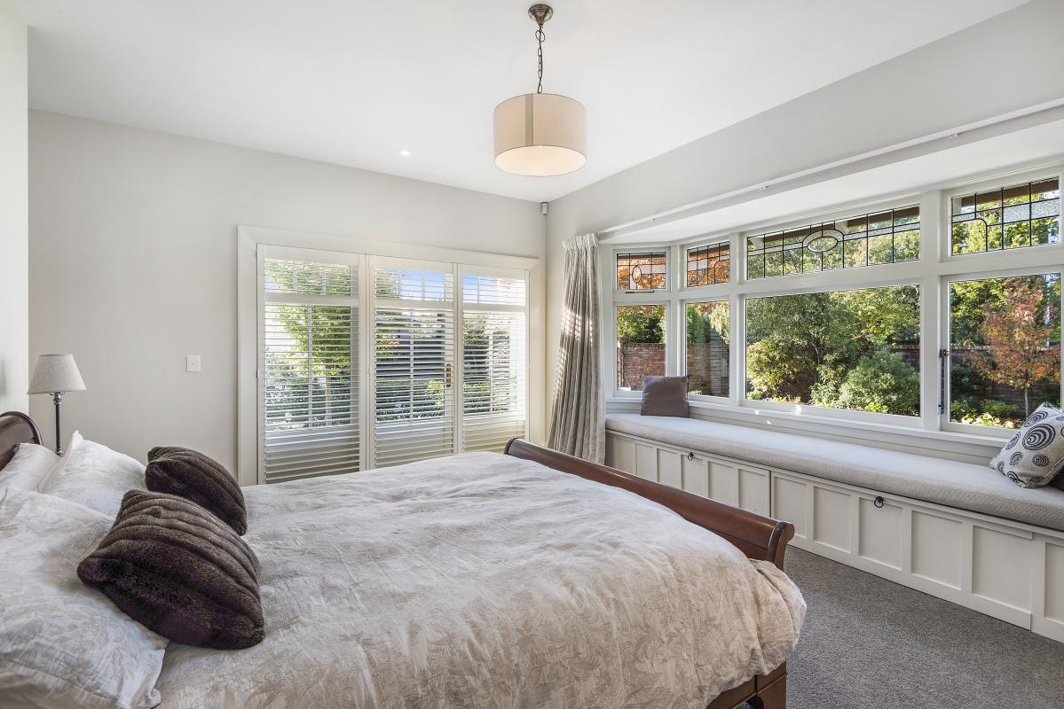 Master bedroom with neutral tones, decorative pendant light and large windows