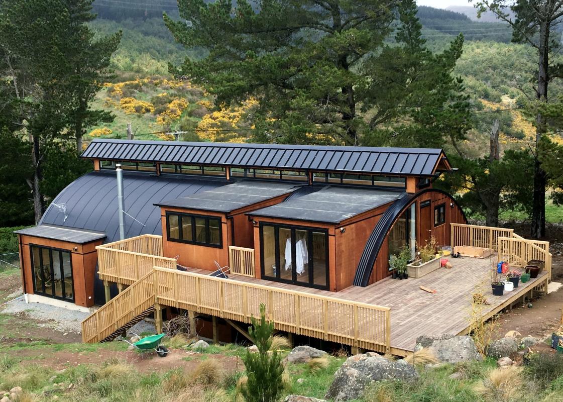 Exterior rear view of the Cashmere Heights home at dusk showing cedar cladding, large glazing and landscaped hillside garden