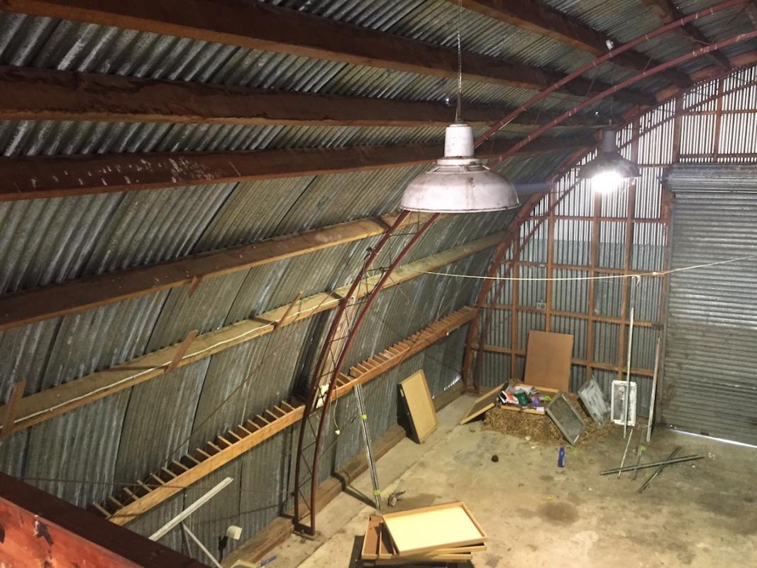 Interior construction view of the Nissen hut showing the original curved steel portal frames and structural timber beams before lining