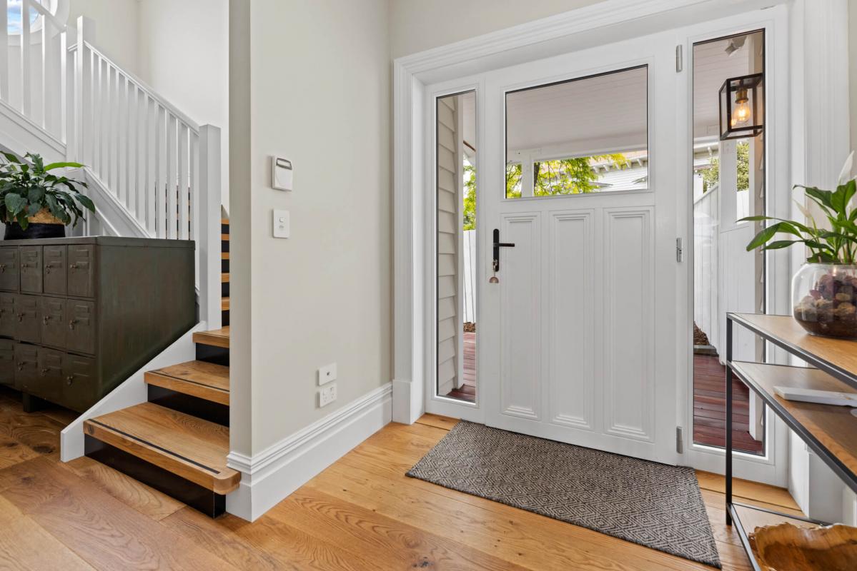 Interior entryway with timber flooring, white walls and staircase detail