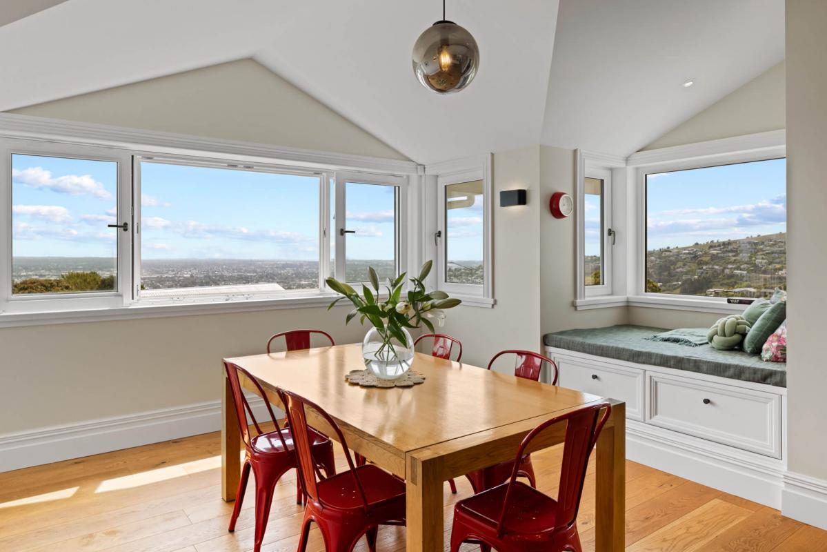 Dining area with timber flooring, classic furnishings, pendant light and large windows with Christchurch city views