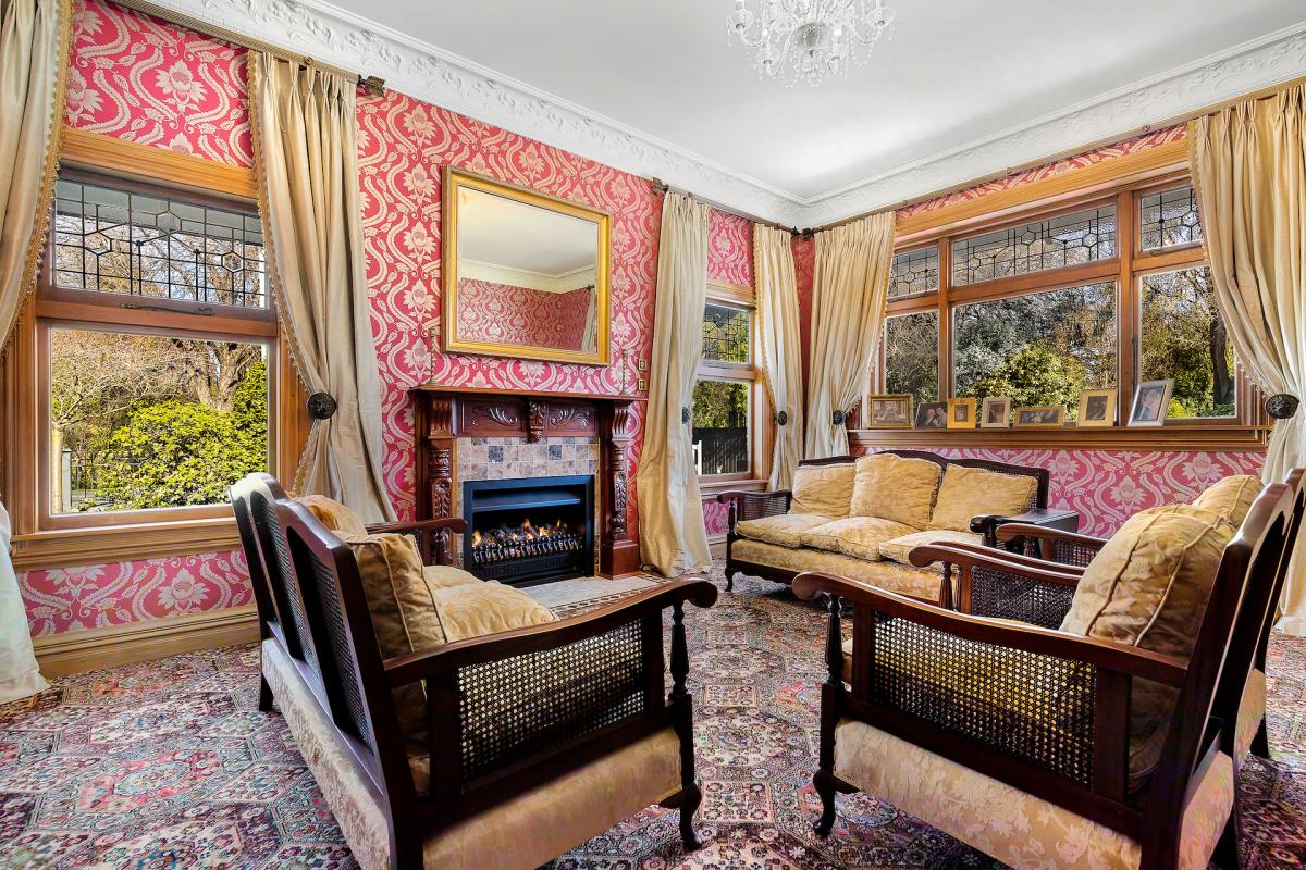 Formal sitting room with rimu timber panelling, period fireplace, patterned carpet and classic furnishings