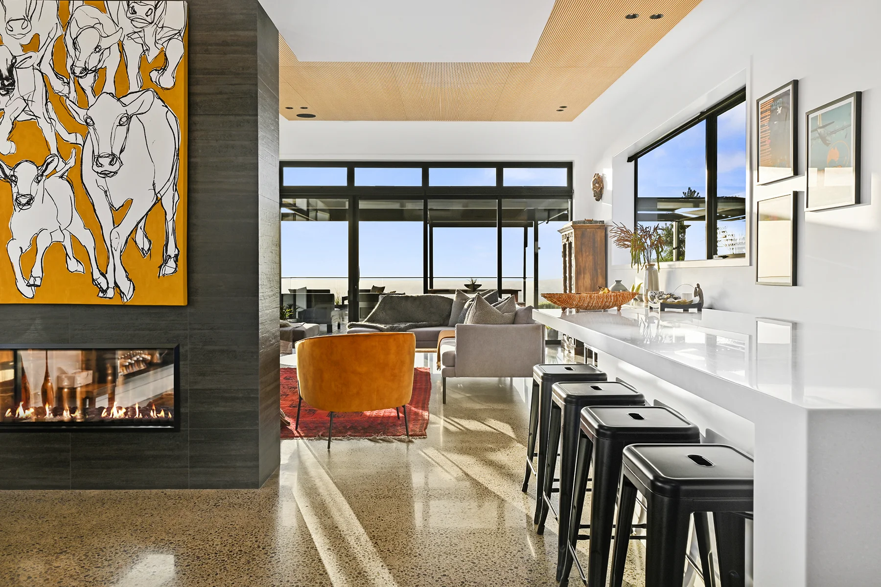 Modern kitchen with dark cabinetry, island bench, orange pendant lights and open-plan dining