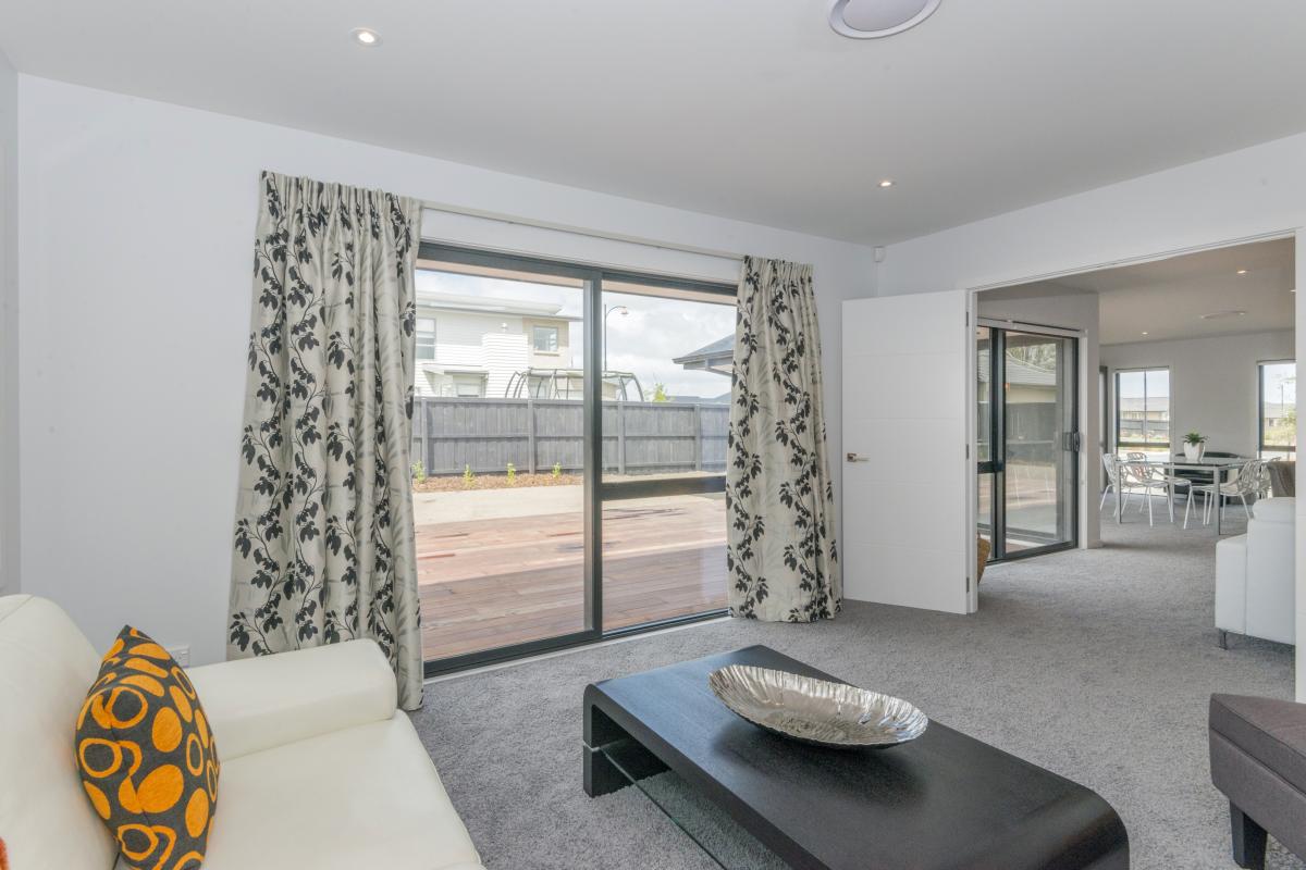 Sitting room with light tones, patterned curtains, carpet and large windows