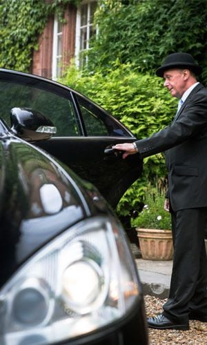 Professional chauffeur opening a car door for a passenger
