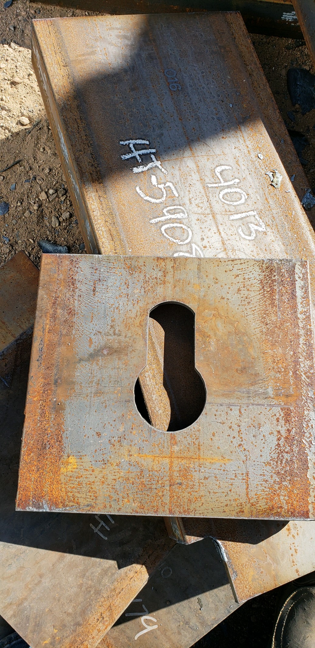 Close-up of a thick steel plate with a precision-cut slot opening, showing surface oxidation from processing