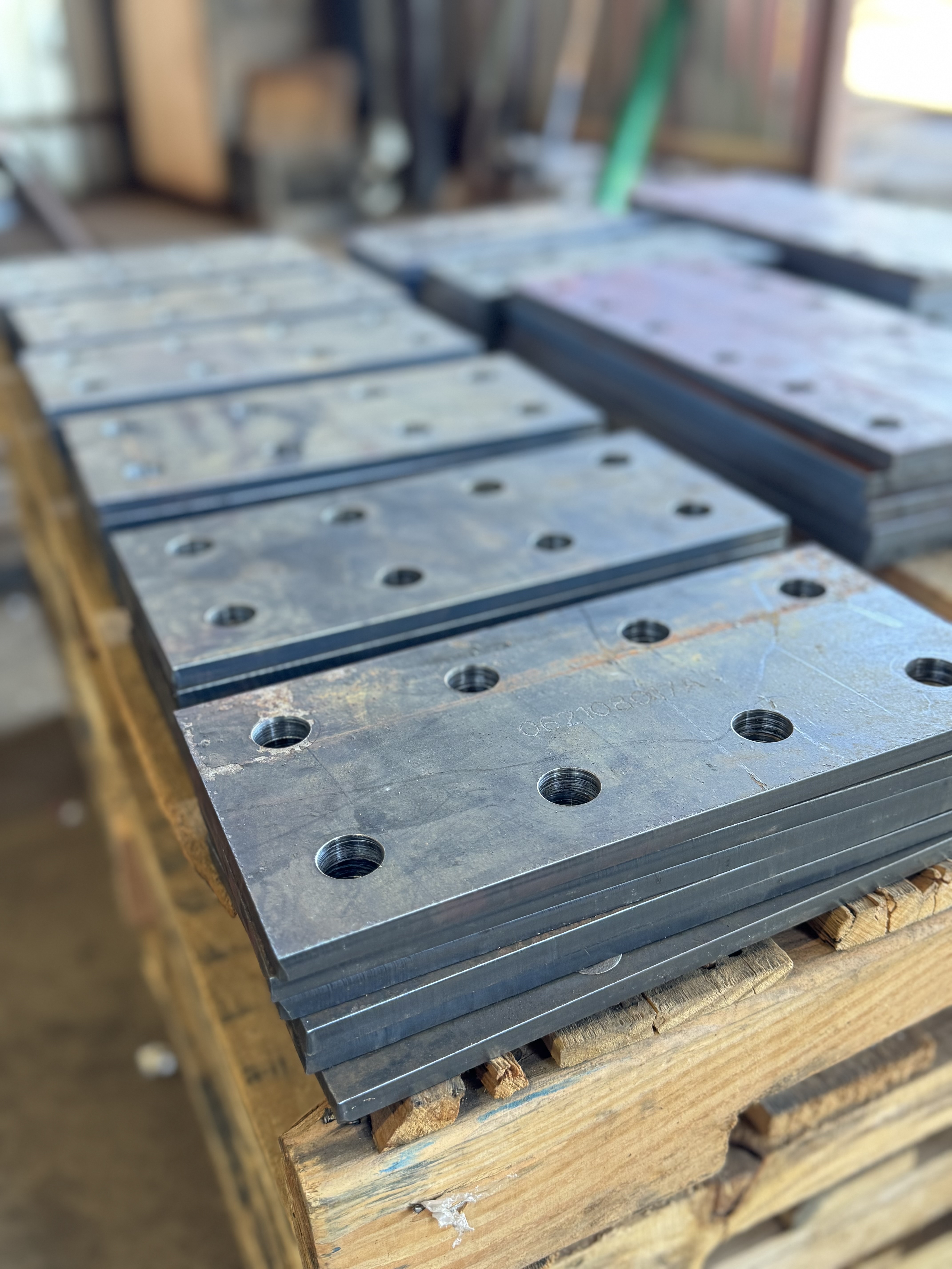 Stacked steel plates with precision-drilled bolt holes, prepared for structural fabrication and assembly
