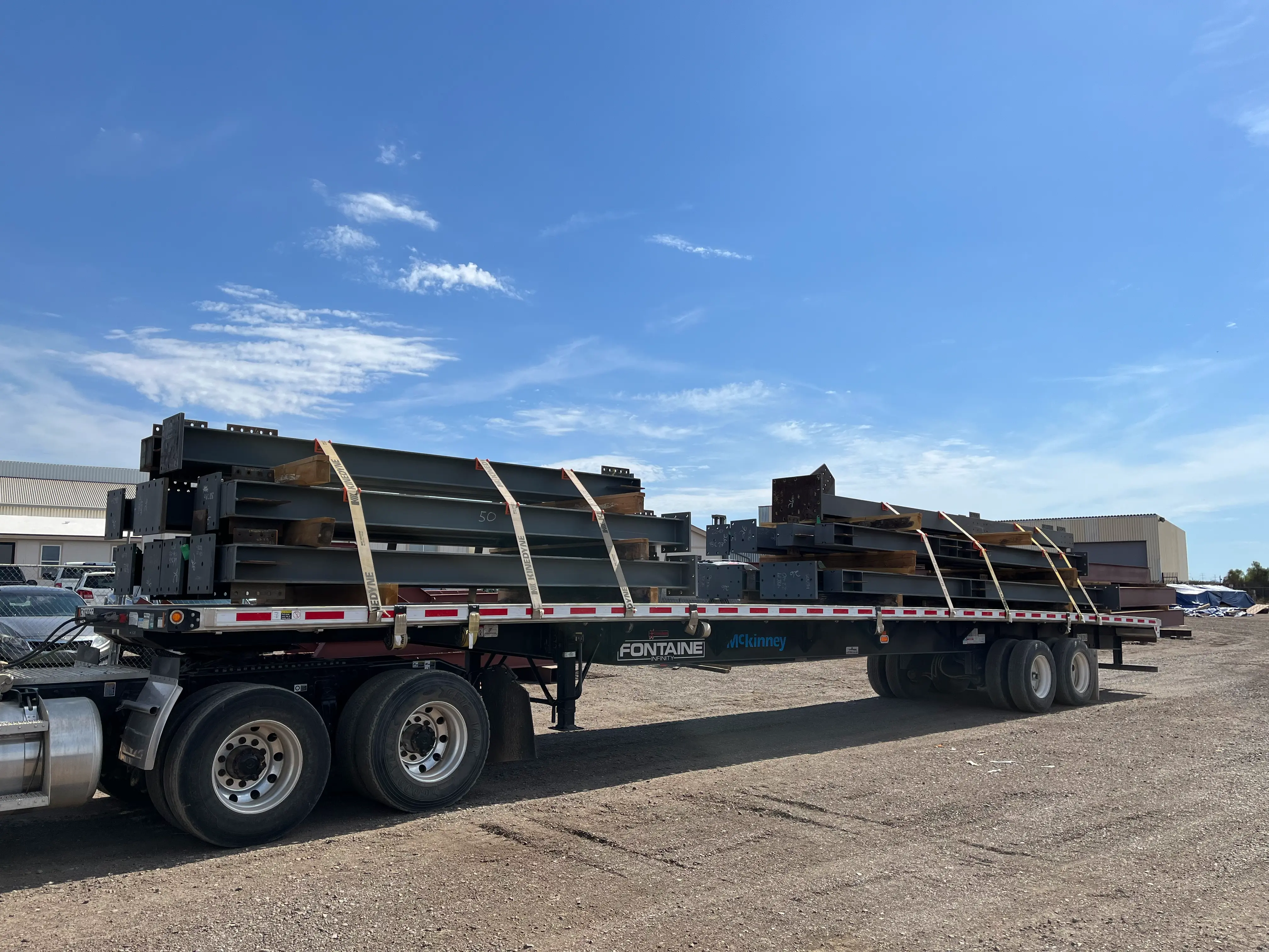Fabricated steel beams loaded and secured on a flatbed trailer for transport