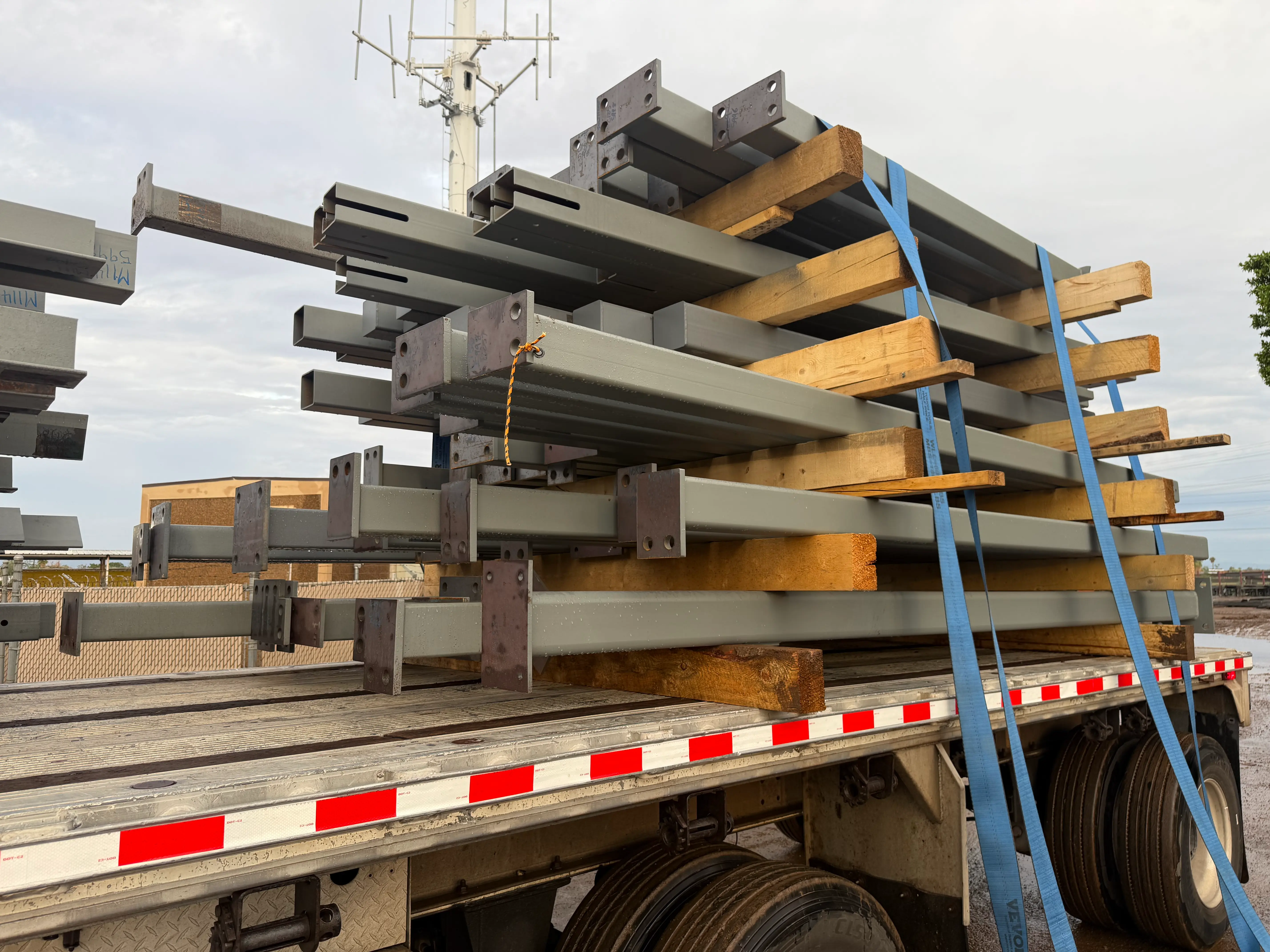 Assorted fabricated steel members stacked and strapped on a flatbed trailer for delivery