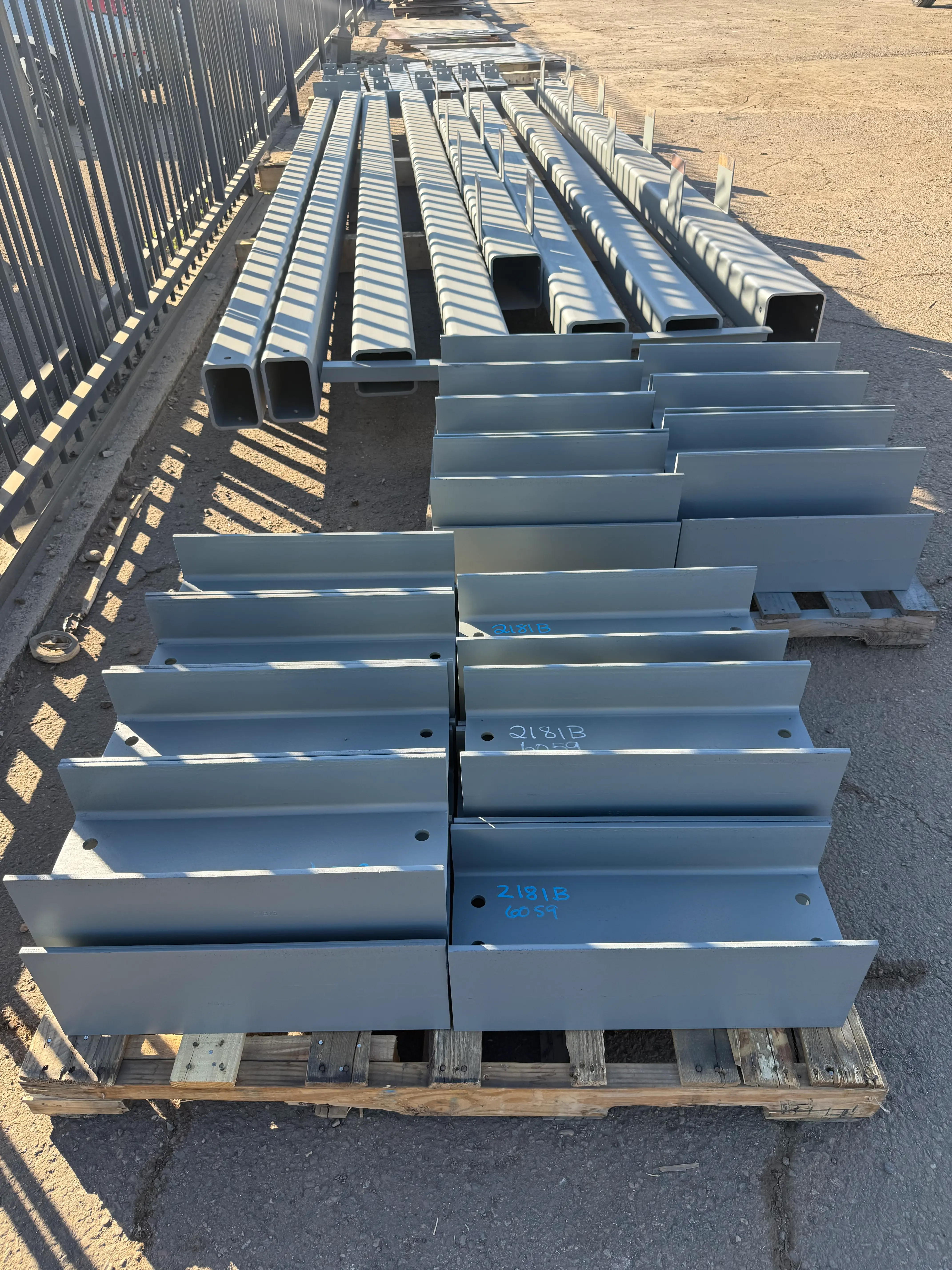 Fabricated steel beams neatly stacked on pallets in a fabrication yard, ready for shipment