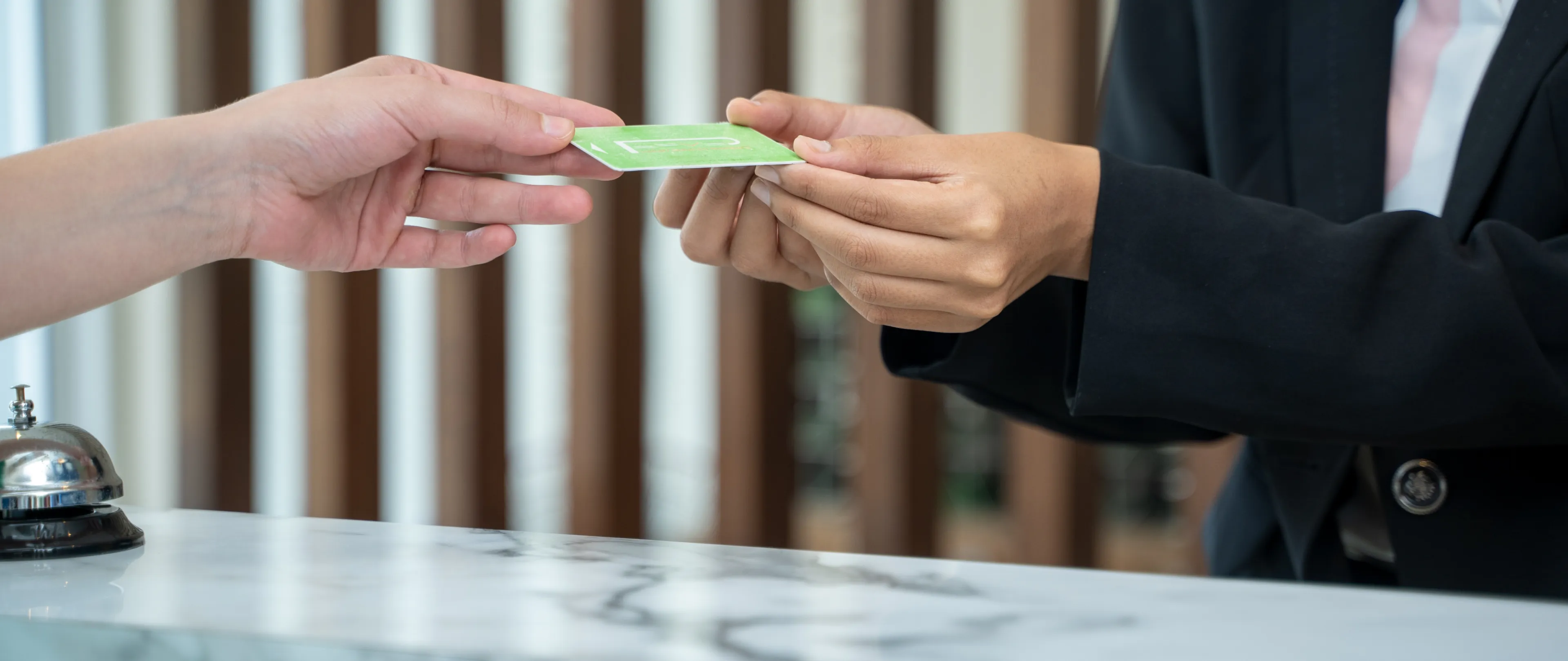 Image of hands exchanging a credit card over a desk.