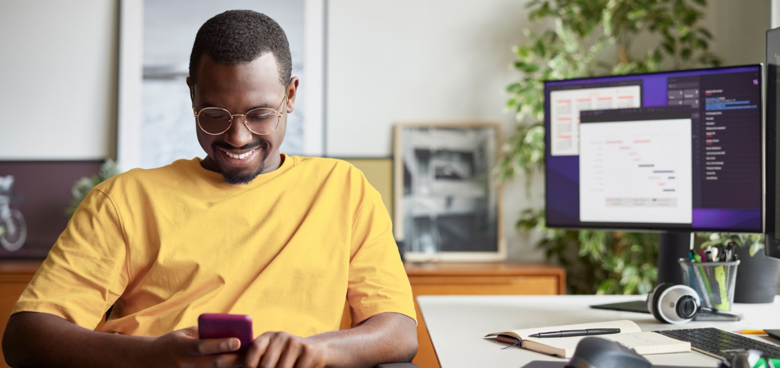 A photo of an employee working from home and smiling at their phone.