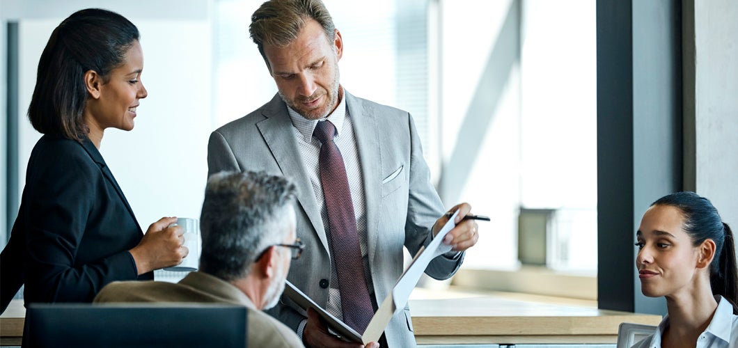 A businessman reading documents next to several colleagues
