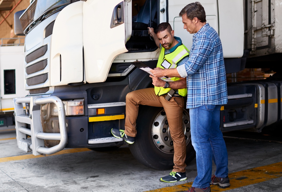 A truck driver and supervisor reviewing notes