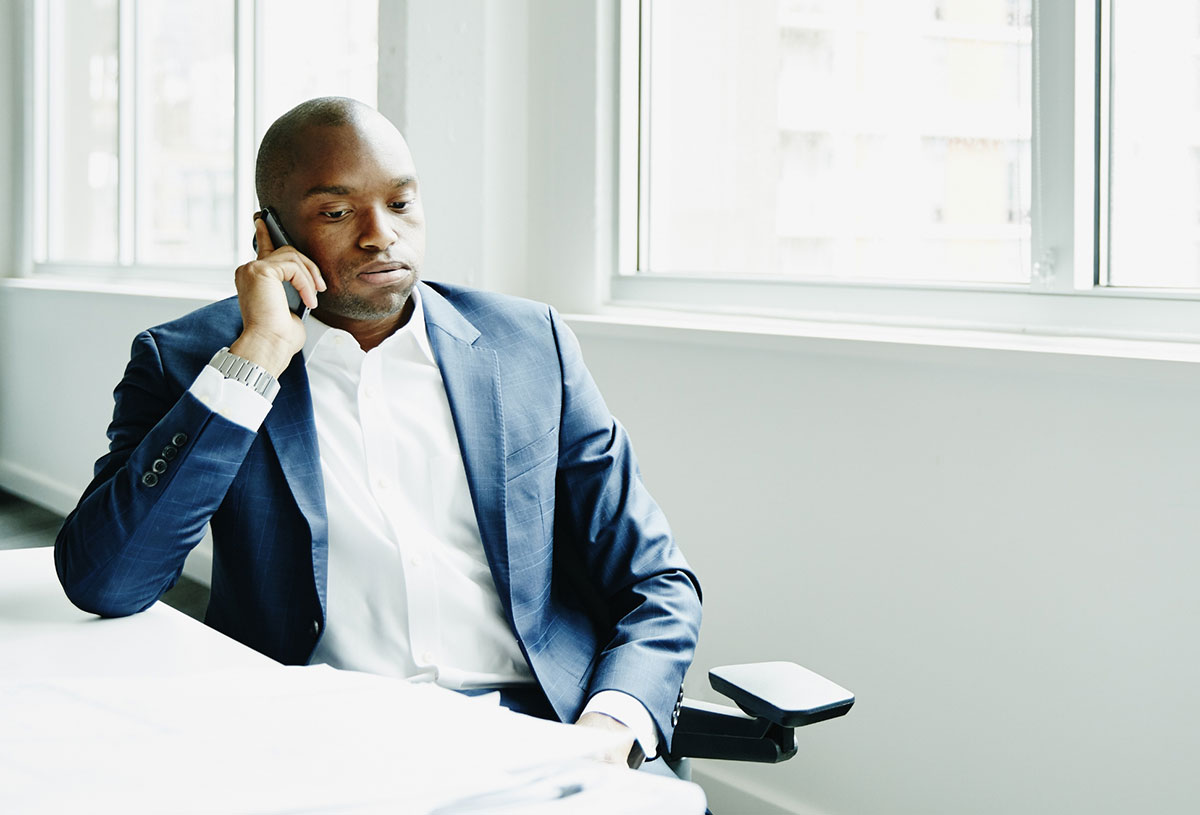 Frustrated man sitting at office workstation while on a smartphone