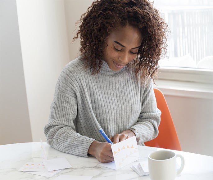 Image of a woman writing a note of appreciation to a teammate