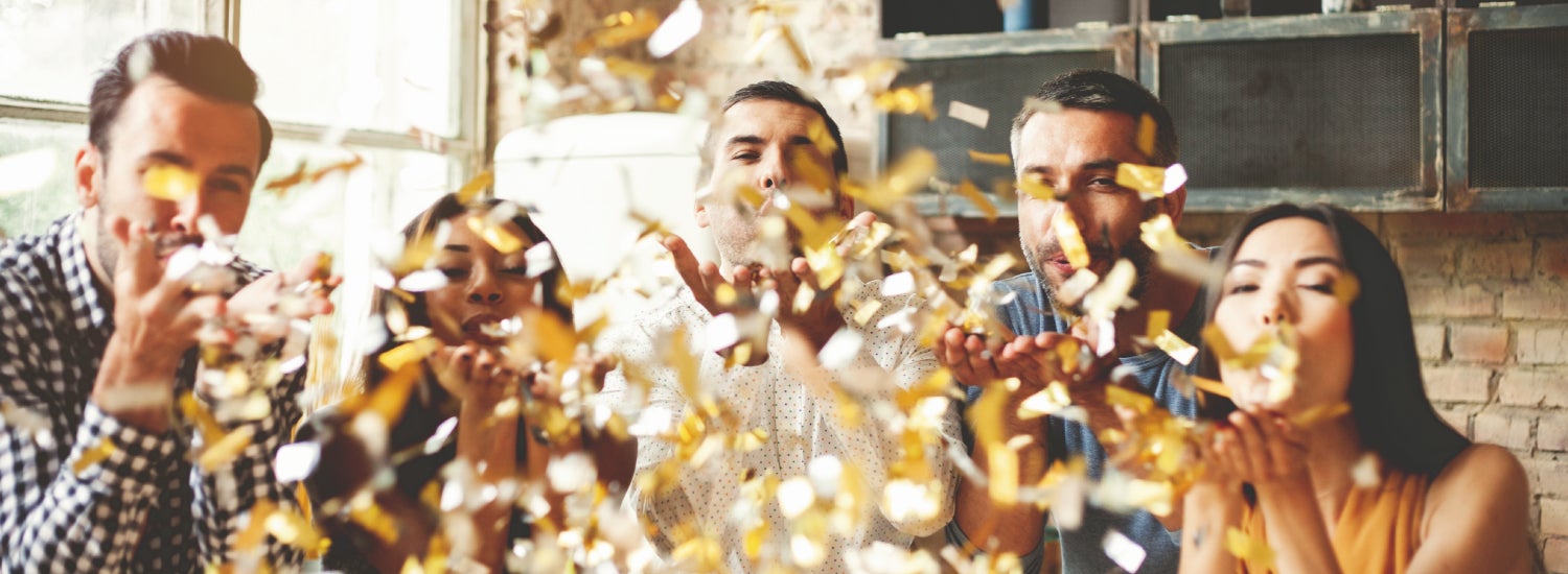 Employees blowing confetti to celebrate a business anniversary