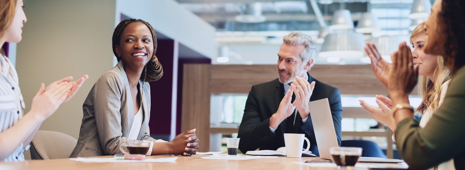 5 employees clapping for their colleague, celebrating a moment of employee recognition.