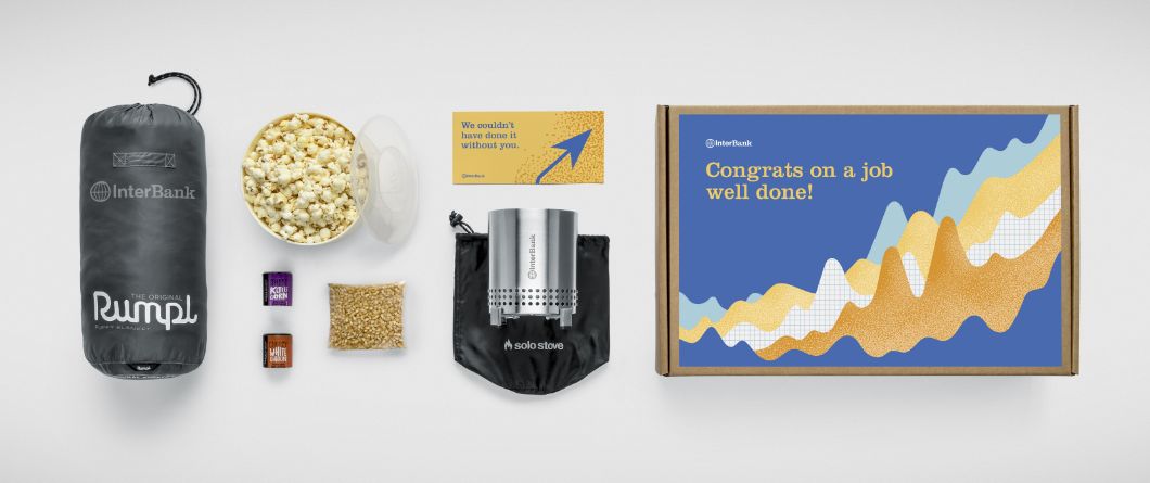 A selection of branded gifts for a congratulatory company swag box, which includes gifts for a camping trip to encourage time away after completing a big project.