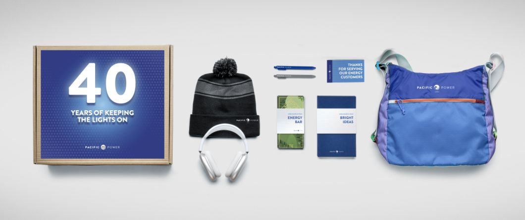 A selection of branded gifts for a major company anniversary or company celebration. This includes a messenger bag, headphones, and an energy bar.