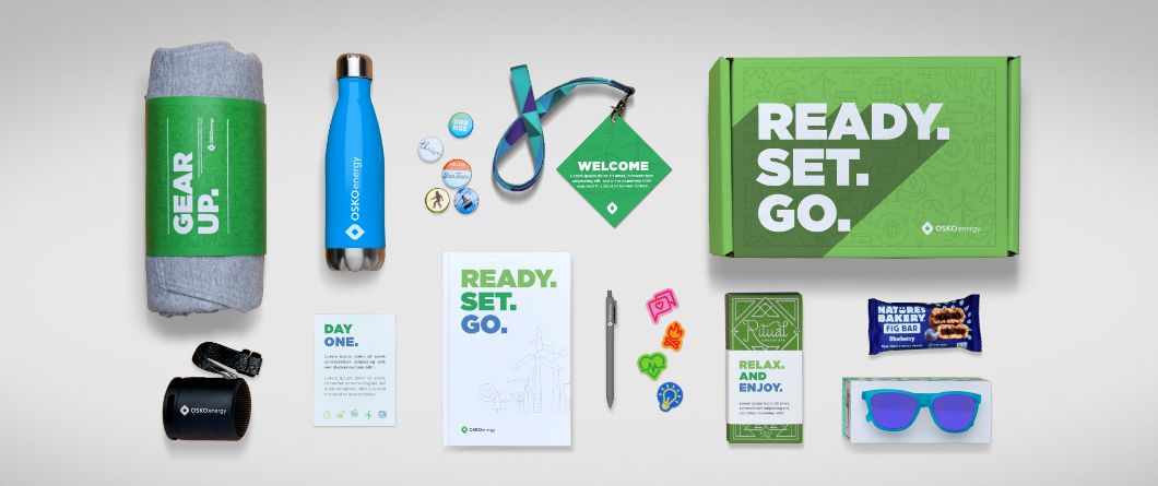 A selection of branded company gifts that can be added to a company onboarding swag box for new employees, including a blanket, water bottle, snacks, and a notebook.