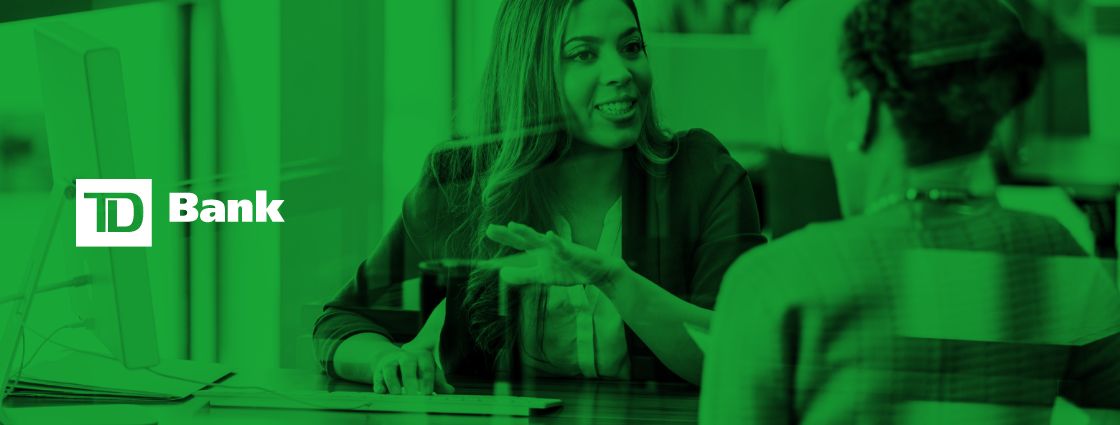 The TD Bank logo overlaid on an image of two employees holding a meeting