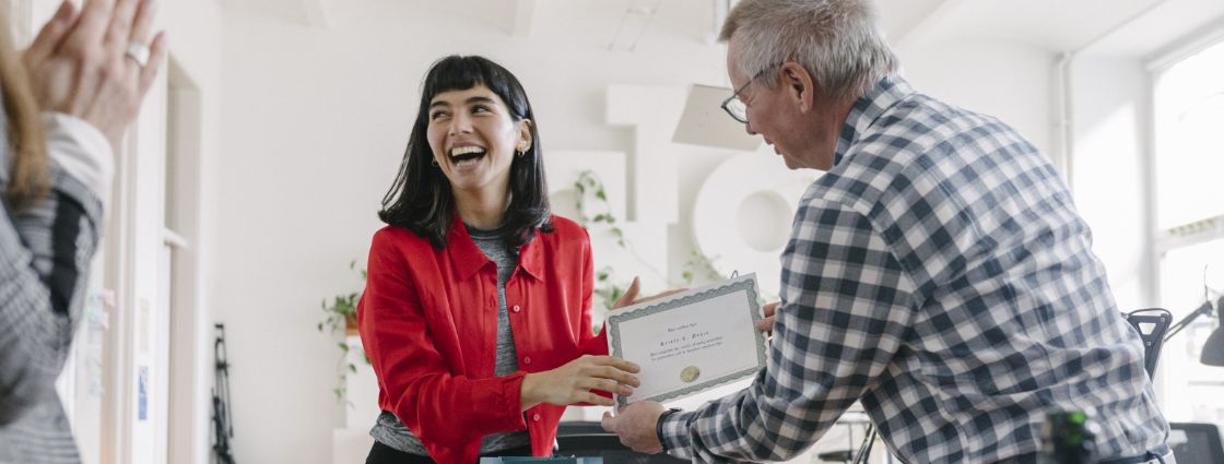 A leader presenting an award to an employee in front of teammates