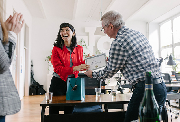 A leader presenting an award to an employee in front of teammates
