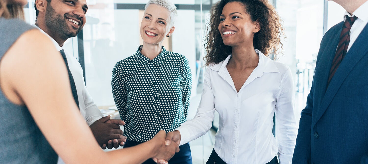 A group of 5 employees shaking hands and laughing