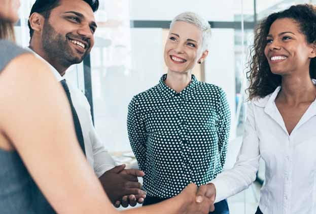 A group of 5 employees shaking hands and laughing