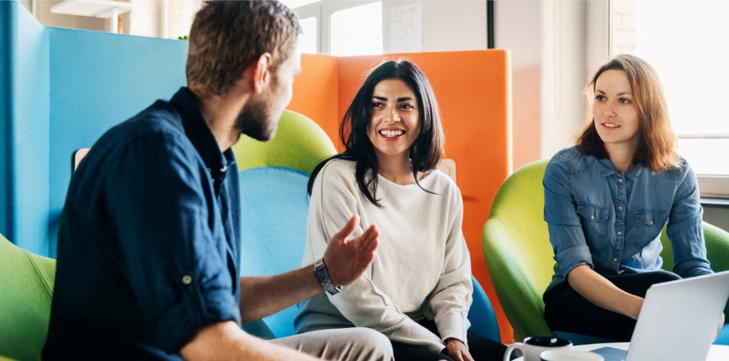 Three teammates meeting in an office around a laptop
