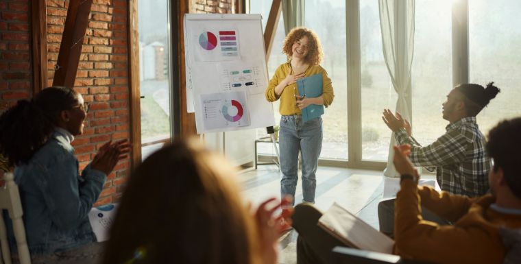 An employee receiving applause and appreciation after presenting to a group