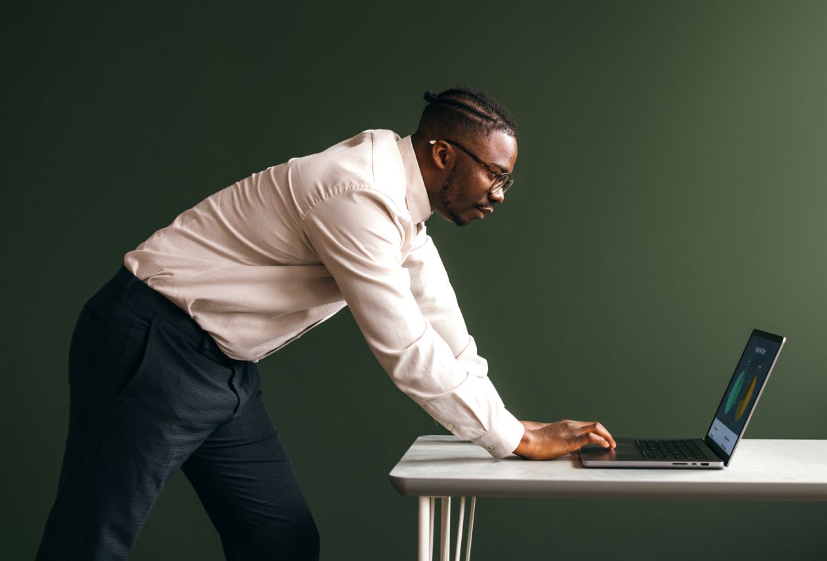 An employee leaning over a desk working on a laptop