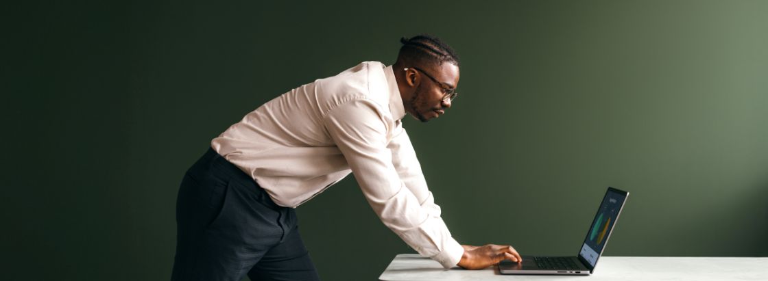 An employee leaning over a desk working on a laptop