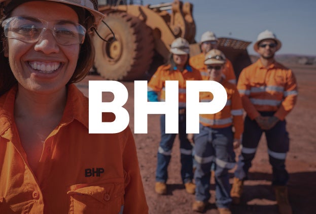BHP employees posing in front of large mining equipment