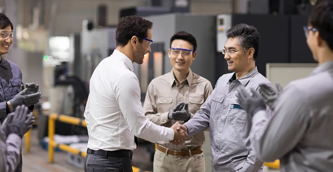 A businessman and engineer shaking hands in a factory