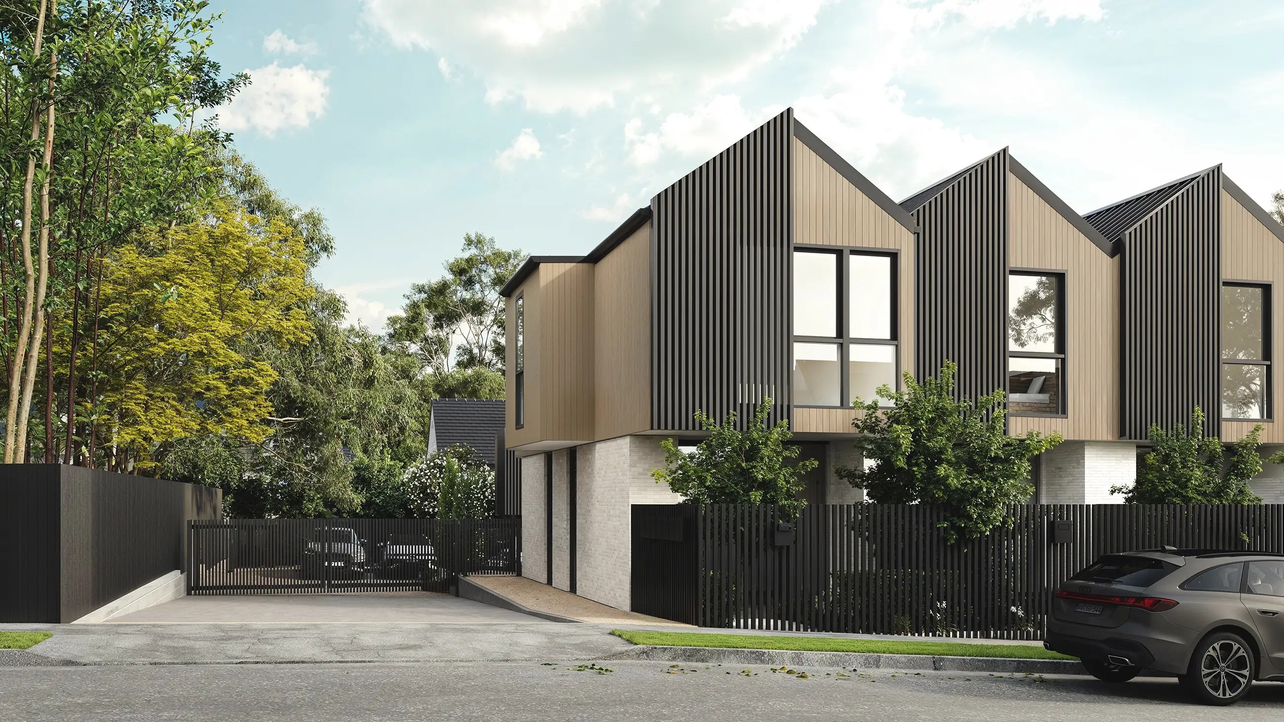 Modern two-story townhouses with black metal fences and a gray car parked on the street.