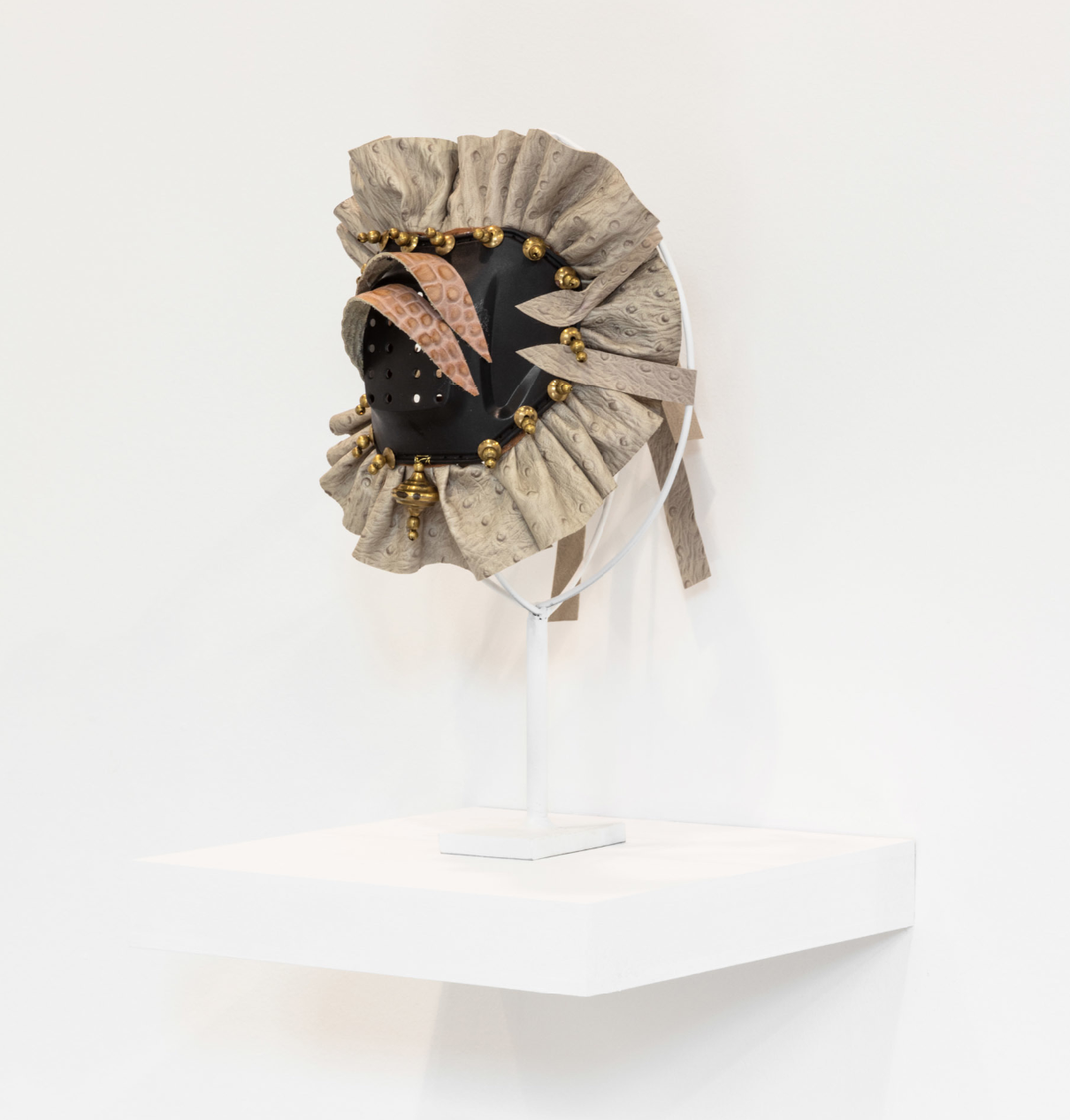 Rajni Perera Mask 3 2019, Motocross elbow pas, brass beads and leather, 12 × 8 × 8 in, 30.5 × 20.3 × 20.3 cm. Courtesy of Patel Brown Gallery.