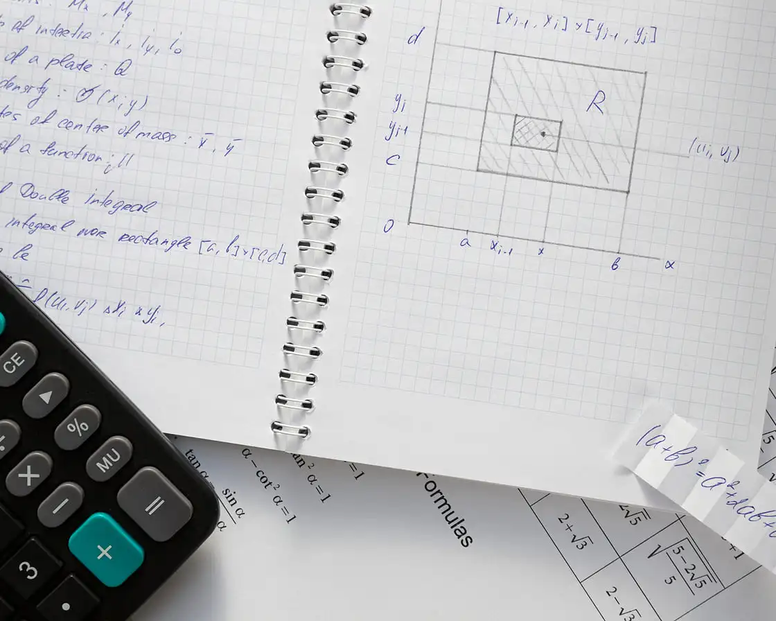 Calculator and notebook on a desk with papers, illustrating a setting for math tutoring activities.