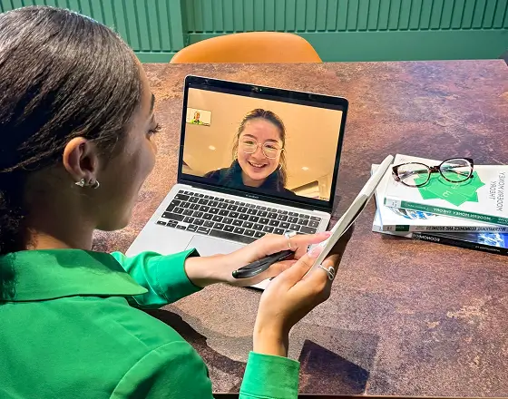 Asha Wadley is on a video call, teaching economics to a student using her laptop.