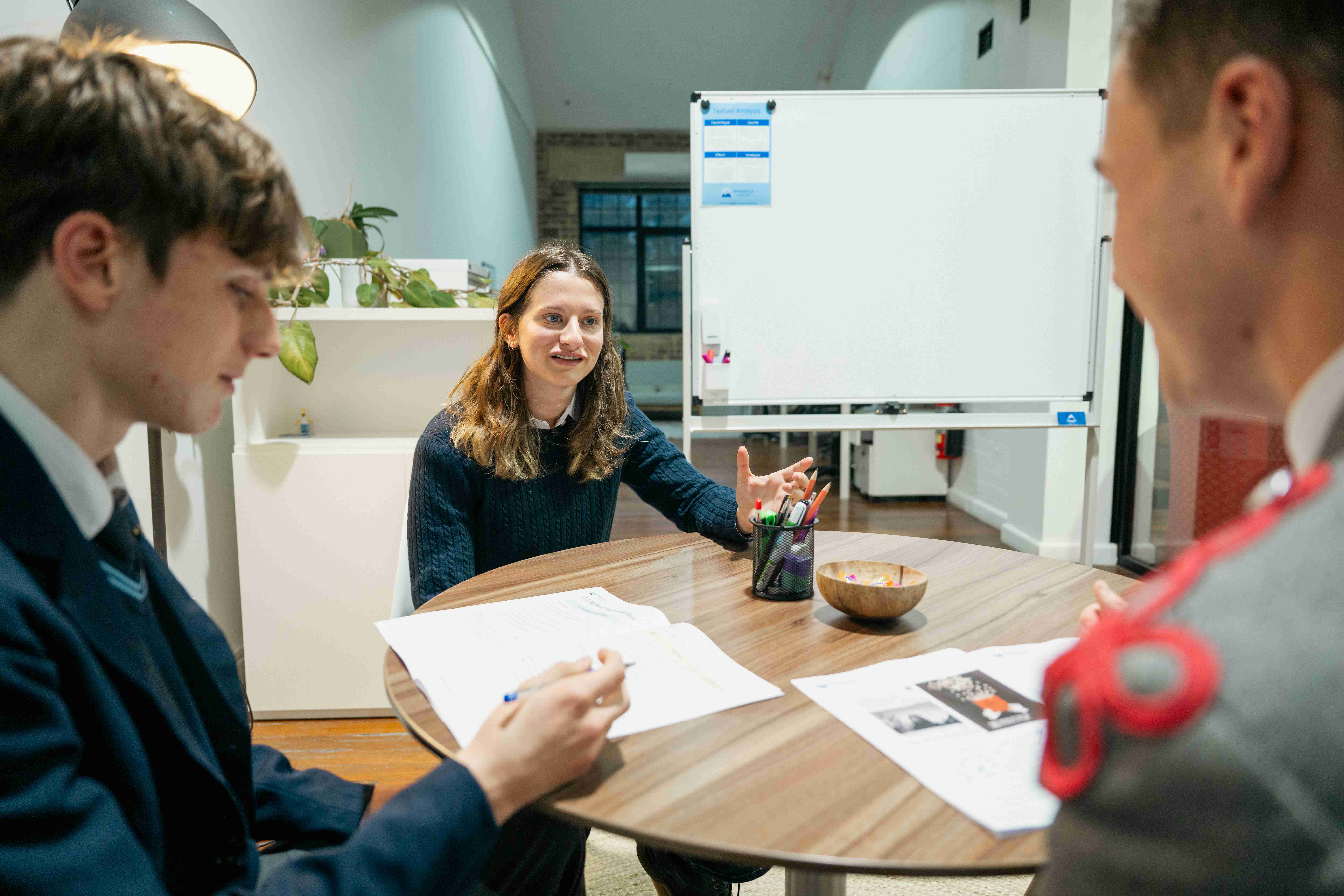 Students discussing Legal and Business Studies with a tutor around a table