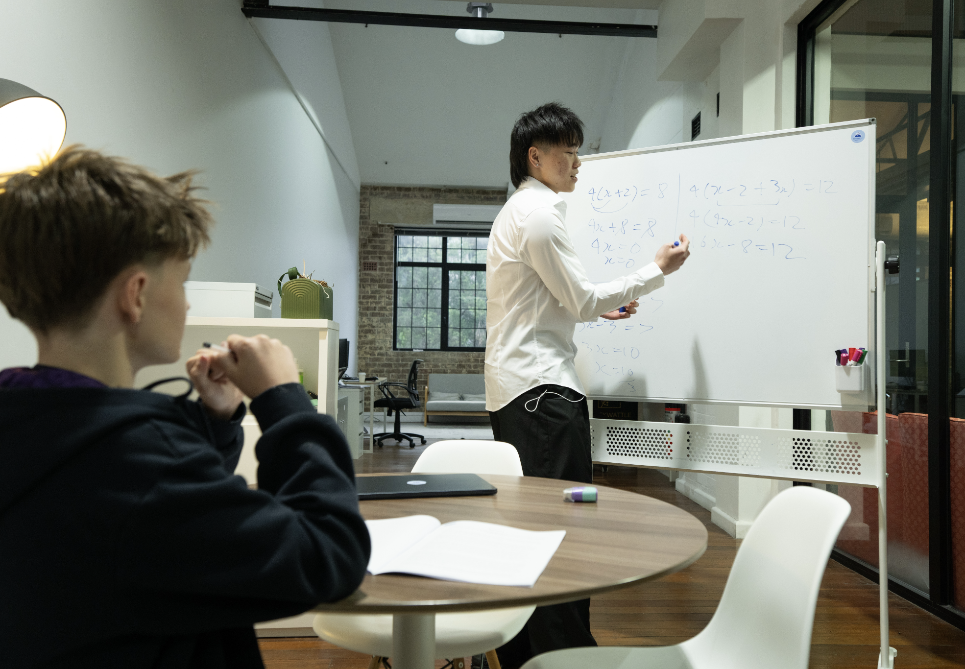 Maths tutor explaining algebra on the whiteboard
