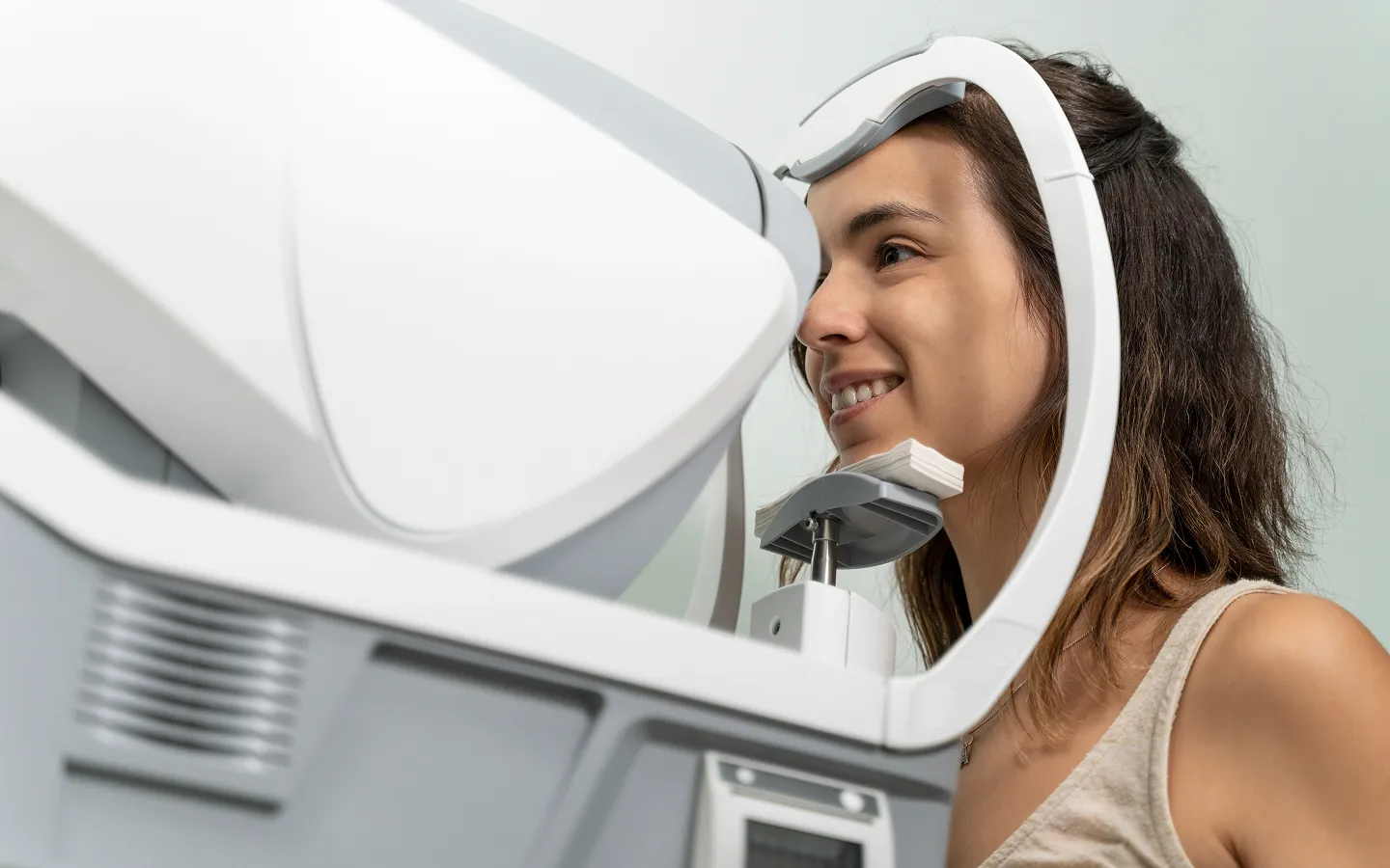 Young woman undergoing an eye examination using an optical coherence tomography machine.