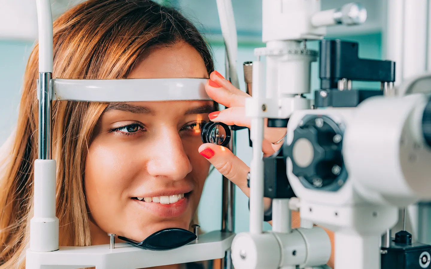 Woman undergoing an eye examination with a slit lamp in an optometrist's office.
