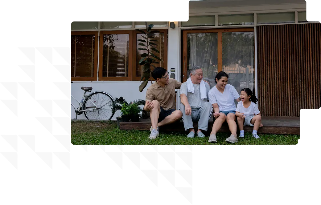 Family of four sitting on a wooden porch smiling and laughing together outside their house.