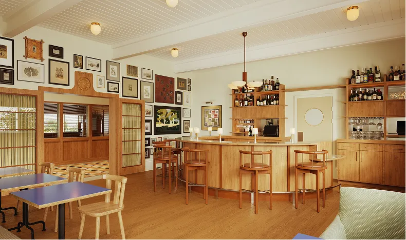 Cozy bar area with wooden stools, shelves of bottles, and framed artwork on walls in a warm-toned room.